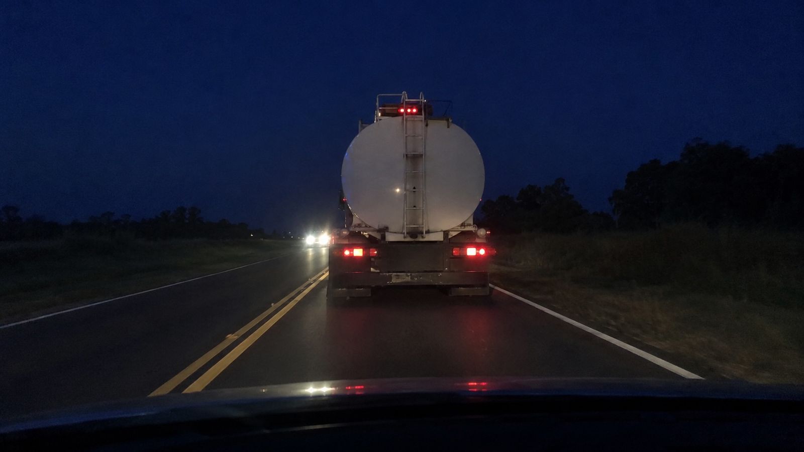Cisterna de noche vista desde el auto que la sigue